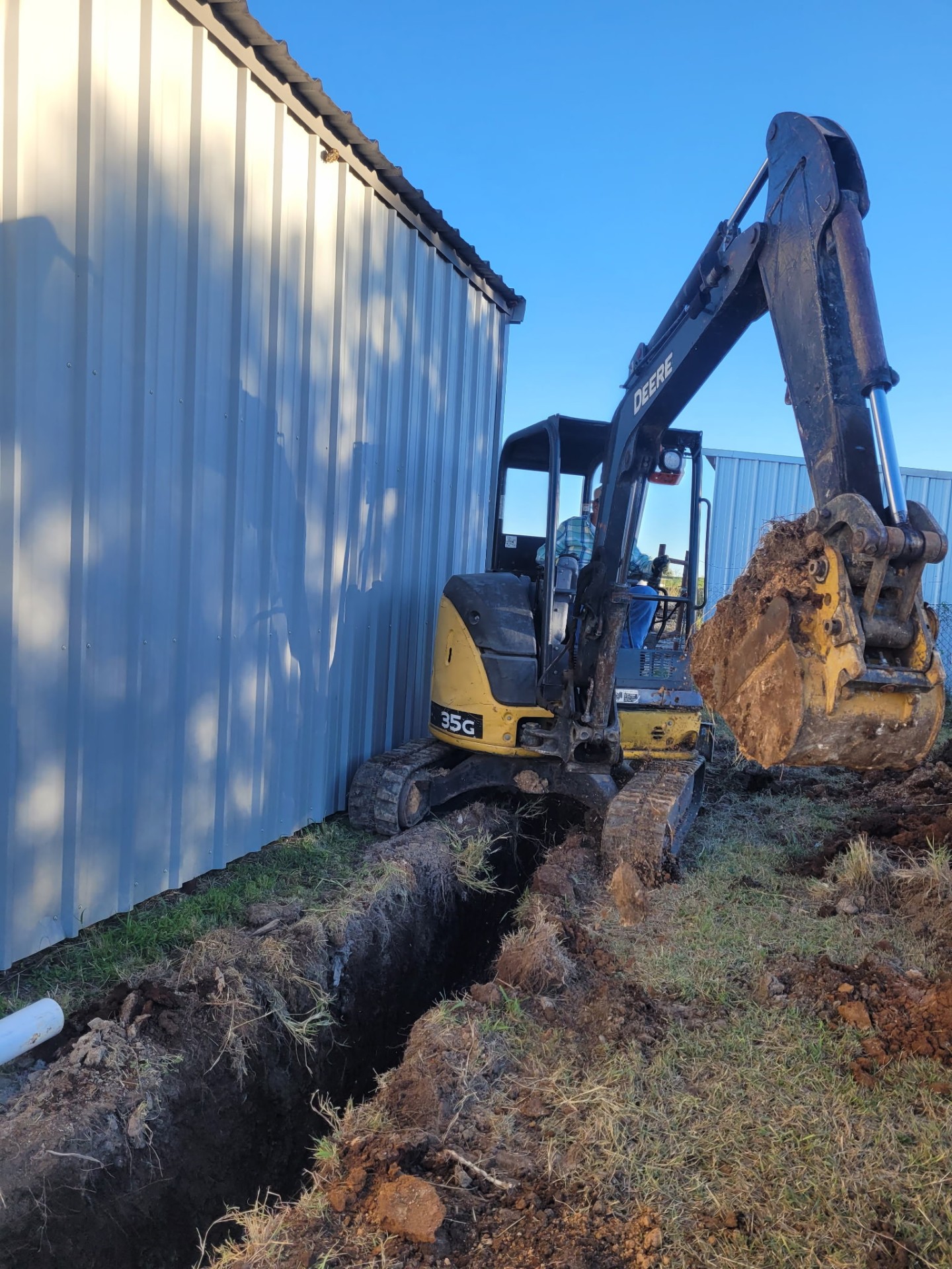 Mini excavator trenching alongside a building