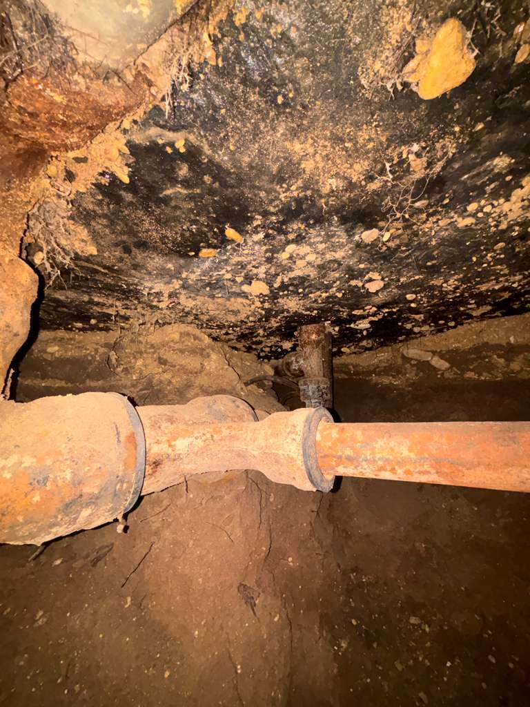 Línea de drenaje de hierro fundido descubierta dentro de túnel bajo losa